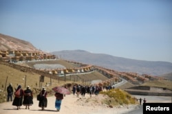 People walk down a street in the town of Nueva Fuerabamba in Apurimac, Peru, Oct. 3, 2017.
