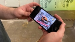 Charles Wilkinson shows his car on his phone.