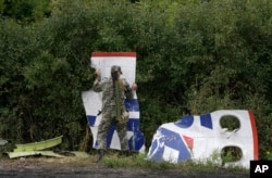 A Pro-Russian rebel stacks pieces of the Malaysia Airlines Flight 17 plane wreckage near the village of Rozsypne, eastern Ukraine, Sept. 9, 2014.