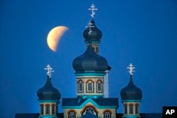 A so-called supermoon is seen at the finish of a lunar eclipse behind an Orthodox church in Turets, Belarus, 110 kilometers (69 miles) west of capital Minsk, Monday, Sept. 28, 2015.