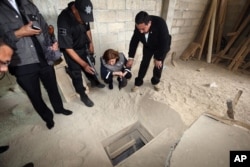 FILE - In this photo provided by Mexico's attorney general, authorities inspect the exit of the tunnel they claim was used by drug lord Joaquin "El Chapo" Guzman to break out of the Altiplano maximum security prison in Almoloya, west of Mexico City, July 12, 201