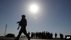 A U.S. soldier, foreground, walks past Syrian children on a road that links to Raqqa, Syria, July 26, 2017.