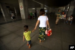 Deng Guilian holds the hand of her son Bo Bo, 3, as they walk through a train station in Ganzhou in southern China's Jiangxi Province, June 7, 2017.