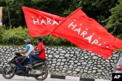 FILE - Supporters ride with flags of Pakatan Harapan (Alliance of Hope) in the southern coastal town of Port Dickson, Oct. 13, 2018.