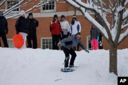 A group of adults and children enjoy an afternoon of sledding and snowboarding on a hill on the campus of Wake Forest University in Winston-Salem, North Carolina, Jan. 17, 2018.