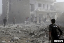 Residents inspect a site damaged by what activists said was a barrel bomb dropped by forces loyal to Syria's president Bashar Al-Assad in Maarat Al-Nouman, south of Idlib, June 8, 2015.