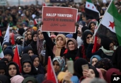 Supporters of a pro-Islamic group stage a protest against the war in Aleppo, at the Bab al-Hawa border crossing with Syria near the southeastern city of Hatay, Turkey, Dec, 17, 2016. The placard reads in Turkish and Arabic: "Aleppo is burning."