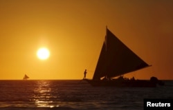 FILE - Tourists catch a glimpse of the sunset while sailing along the island of Boracay, central Philippines January 17, 2016.