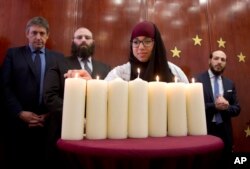 An organizer leads children holding signs out of the Molenbeek district during a march against hate in Brussels on Sunday, April 17, 2016.
