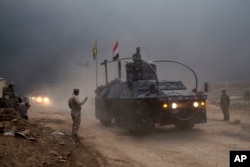 An Iraqi Federal Police vehicle passes through a checkpoint in Qayyarah, 50 kilometers south of Mosul, Iraq, Oct. 26, 2016. Islamic State militants have been going door to door in farming communities south of Mosul, ordering people at gunpoint to follow them north into the city and apparently using them as human shields as they retreat from Iraqi forces.