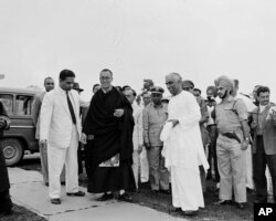 FILE - An unidentified Indian official, right, greets Tibetan spiritual leader Dalai Lama, in black robe, at a military camp on the border of Assam and the Northeast Frontier Agency area, April 18, 1959, shortly after the Dalai Lama's arrival in India.
