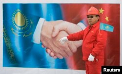 រូបឯកសារ៖ វិស្វករចិនឈរមុខបដាដ៏ធំមួយក្នុងពិធីសម្ពោធដំណើរការសាងសងបំពង់បង្ហូរឧស្ម័នរវាងប្រទេសចិននិងតួកមេនីស្ថាន នៅទីក្រុង Almaty នៃប្រទេសកាហ្សាក់ស្ថាន កាលពីថ្ងៃទី ១២ ខែធ្នូ ឆ្នាំ ២០០៩។