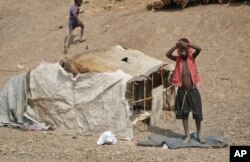 FILE - A young boy stands outside his small shelter in the United Nations protection of civilians site in Bentiu, South Sudan, Dec. 9, 2018.