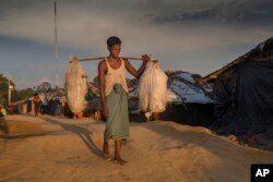 A Rohingya Muslim man Bodi-Ur-Rehman stops for a photograph as he arrives carrying his belongings at Kutupalong refugee camp, Bangladesh, Sept. 15, 2017.