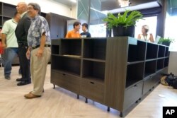 FILE - James H.Q. Lee, foreground left, CEO of medical marijuana dispensary Aloha Green, talks with employees amid empty shelves, June 6, 2017, in Honolulu. Hawaii's Legislature approved medical marijuana in 2000, but it took island lawmakers another 15 years to set up a dispensary system, and longer still to certify labs to run required safety tests.
