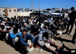 African illegal migrants wait to receive medial assistance after being rescued by coastal guards on a port in Tripoli, Libya, Monday, April 11, 2016.