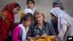 Dalam foto tertanggal 1/10/2011 ini, wartawan AP Kathy Gannon duduk dengan anak-anak perempuan di sebuah sekolah di Kandahar, Afghanistan.
