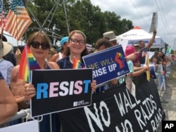 Women hold signs opposing President Donald Trump's policies while joining anti-Trump demonstrators outside Suffolk Community College in Brentwood, New York, July 28, 2017.