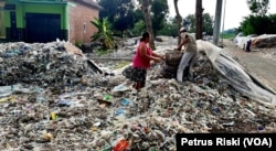 Supiati dan Saji mengangkut sampah plastik impor di pekarangan mereka, di Desa Bangun, Kecamatan Pungging, Kabupaten Mojokerto, untuk kemudian disortir dan dijual kembali, Juni 2019. (Foto: Petrus Riski/VOA)