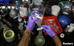 FILE - An employee works with a funnel inside a laboratory in India, Aug. 11, 2014.