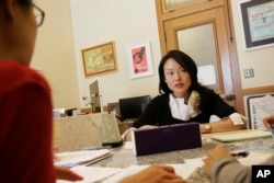 FILE - City supervisor Jane Kim talks to members of her staff as she is interviewed at City Hall in San Francisco, June 26, 2017.