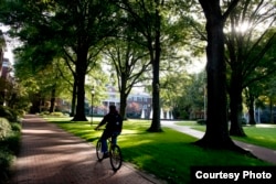 A student rides a bicycle across campus at Elon University in Elon, North Carolina.