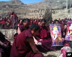Monks praying in front of body at a cremation site