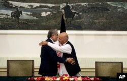 Afghanistan's presidential election candidates Abdullah Abdullah, left, and Ashraf Ghani Ahmadzai, right, hug after signing a power-sharing deal at presidential palace in Kabul, Afghanistan, Sept. 21, 2014.