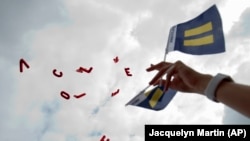 Balloons that spelled out "HRC," Human Rights Campaign, and "love" float in the air as they are released outside of the Supreme Court in Washington