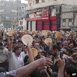 In this citizen journalism image made on a mobile phone and acquired by AP, May 3, 2011, Syrian men carry pieces of bread during a protest against Syrian President Bashar Assad's regime, in the coastal town of Banias