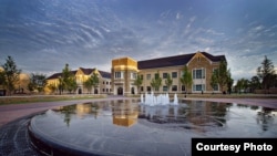 Campus buildings reflect in the water of the fountain at Samson Plaza at the University of Tulsa.
