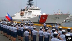 Philippine Coast Guard personnel salute to welcome the U.S. Coast Guard National Security Cutter Bertholf (WMSL 750) as it arrives for a port call in the first visit by a U.S. cutter in over seven years, Wednesday, May 15, 2019 in Manila, Philippines. (AP