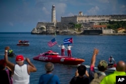 FILE - Tourists stand aboard their speedboat, backdropped by "El Morro" castle, in Havana, Cuba, Aug. 17, 2017.