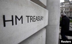 FILE - A worker enters the Treasury building in London, Britain, March 7, 2017.