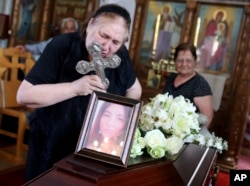 The mother of Livia Florentina Bunea leans over to kiss a cross during the funeral of Bunea, 36, from Romania and her daughter Elena Natalia, 8, at a church in Arediou, Cyprus, June 13, 2019. The mother and daughter are believed to have been victims of a confessed serial killer.