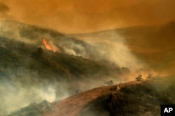 Bulldozer operators and their machines build containment lines while battling the River fire in Lakeport, Calif. The operators who steer heavy bulldozers across steep ridges face many dangers, from the flames themselves to unsteady dirt and rocky terrain.
