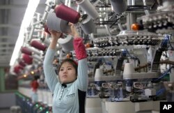 FILE - A North Korean worker carries a reel of thread at the Pyongyang Sock Factory in Pyongyang, North Korea, Jan. 9, 2017.