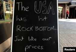 A shopper walks behind a sign on display outside a wine shop in Sydney, Australia Nov. 10, 2016 that comments on the recent U.S. election in which Republican candidate Donald Trump was victorious.