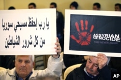FILE - Assyrians citizens hold placards during a sit-in for abducted Christians in Syria and Iraq, at a church in Sabtiyesh area east Beirut, Lebanon, Feb. 26, 2015.