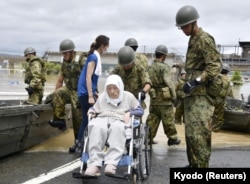 An elderly man in a wheelchair is rescued from a flooded area in Kurashiki, Okayama Prefecture, Japan, July 8, 2018.