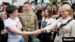 Ukrainian servicewoman Nadiya Savchenko shakes hands with Ukrainian former Prime Minister and leader of Batkivshchyna (Fatherland) party Yulia Tymoshenko at Boryspil International airport outside Kyiv, May 25, 2016.