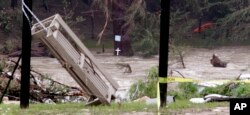 A cross sits at water-level of the still flooding Blanco River and in view of debris from a flood days earlier, Tuesday, May 26, 2015, in Wimberley, Texas.