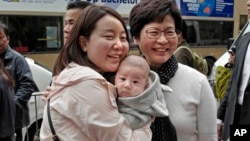 Hong Kong's chief executive elect Carrie Lam (center right) poses with local residents in Hong Kong, March 27, 2017.