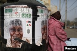 FILE PHOTO: A man sits next to a campaign poster of Atiku Abubakar, leader of the People's Democratic Party, days before the presidential election in Kano, Nigeria, Feb. 17, 2019.