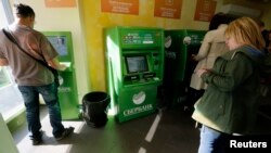 Orang-orang menggunakan mesin ATM di dalam cabang Sberbank di St. Petersburg, 16 September 2014. (Foto: Reuters)