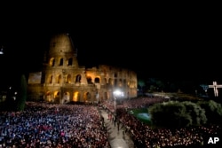 Faithful attend the Via Crucis (Way of the Cross) torchlight procession celebrated by Pope Francis in front of the Colosseum on Good Friday in Rome, April 18, 2014.