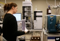 In this Aug. 10, 2015, photo, Christine Jelinek, a postdoctoral fellow at Johns Hopkins University, prepares to load a tray of vials containing cerebral spinal fluid into a liquid chromatograph in Baltimore.