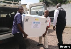 Congolese Health Ministry officials carry the first batch of experimental Ebola vaccines in Kinshasa, Democratic Republic of Congo, May 16, 2018.