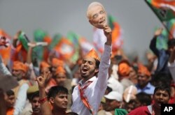 Warga India pendukung PM Narendra Modi membawa topeng Modi dalam acara kampanye di kota Meerut, Uttar Pradesh.