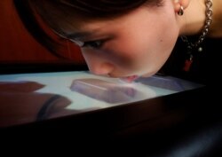 Mahasiswa Universitas Meiji Yuki Hou menjilat layar Taste the TV (TTTV), sebuah prototipe layar TV yang dapat dijilat yang dapat meniru rasa berbagai makanan, saat demonstrasi di universitas di Tokyo, Jepang, 22 Desember 2021. (Foto: REUTERS/Kim Kyung-Hoo